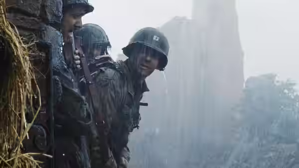 soldiers in helmets crouching beside a rocky cliff in the rain