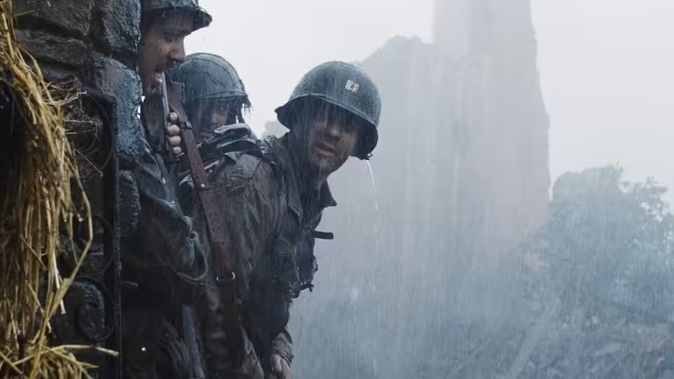 soldiers in helmets crouching beside a rocky cliff in the rain