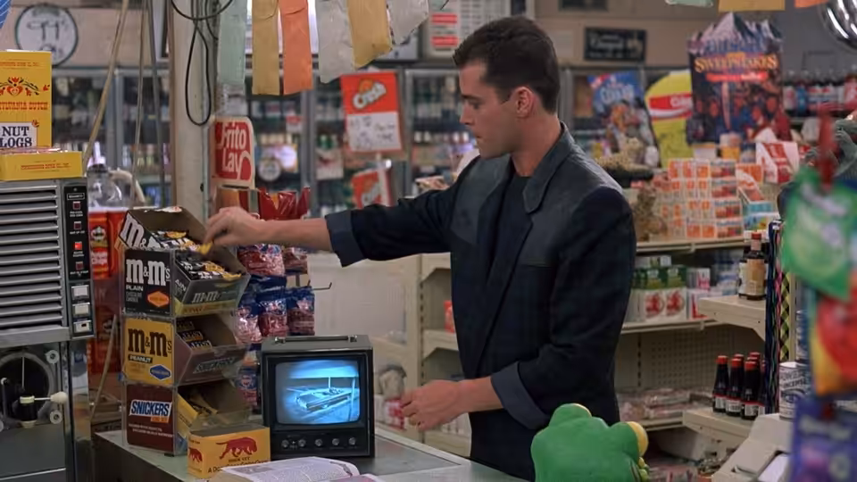 Charles Driggs reaches across the counter for M&M's in a convenience store