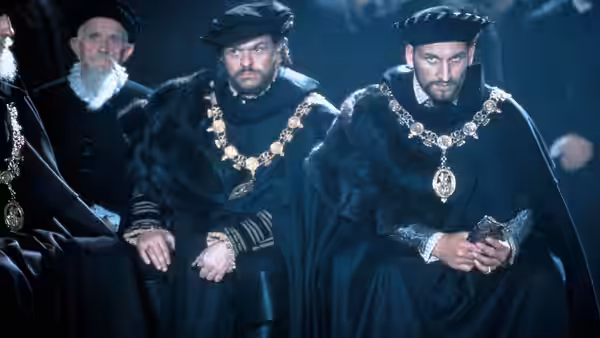 Two men in dark fur-trimmed robes with medallions seated together