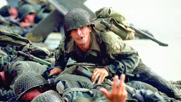 Griff (Mark Hamill) crawls over fallen soldiers with a rifle slung across his back