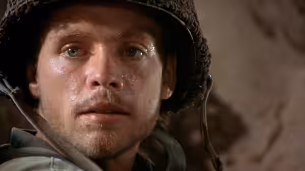 A young soldier in a netted helmet looks tensely offscreen