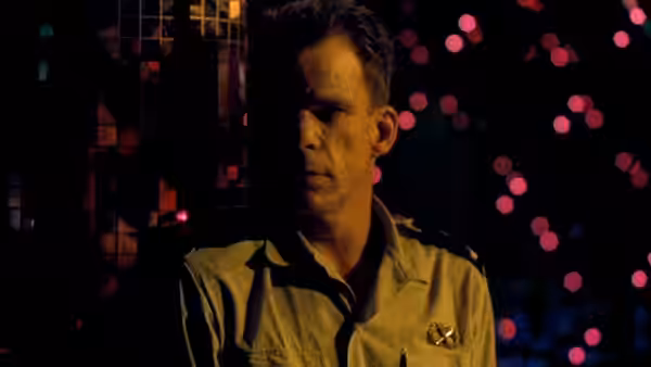 Galoup (Denis Lavant) stands in uniform amid colored lights