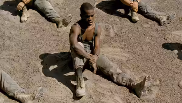 A Legionnaire sits on the sand as fellow soldiers lie around him