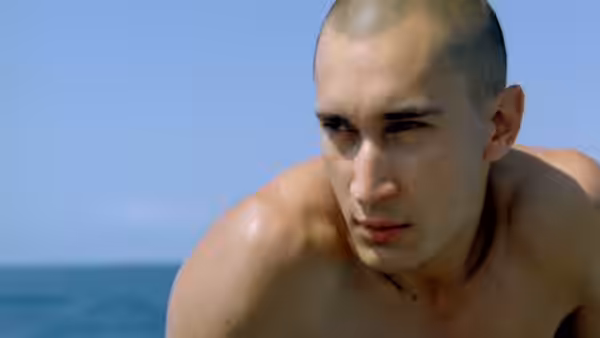 A young Legionnaire crouches by the sea, looking toward the shore