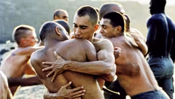Legionnaires grapple and embrace during a shirtless training exercise