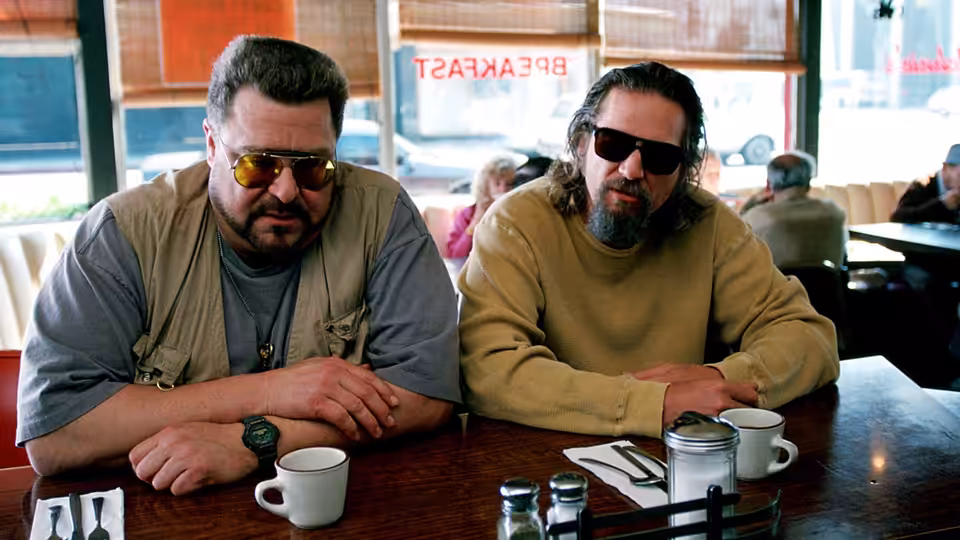 Walter Sobchak (John Goodman) and The Dude (Jeff Bridges) seated at a diner table