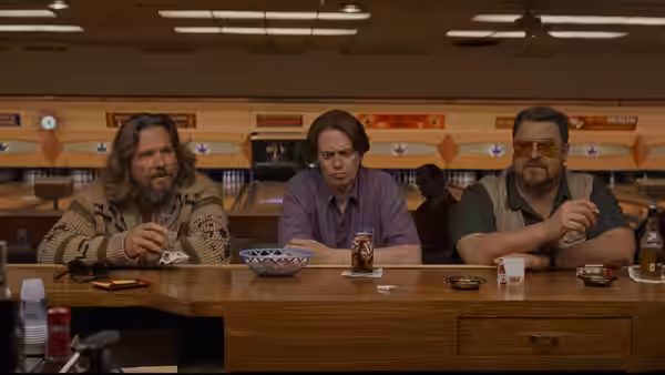 The Dude (Jeff Bridges), Brandt (Philip Seymour Hoffman) and Walter Sobchak (John Goodman) at a bowling alley counter