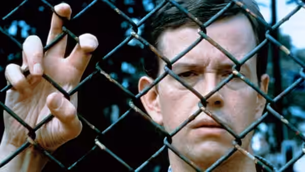 Allen (Philip Seymour Hoffman) gripping a chain-link fence with both hands