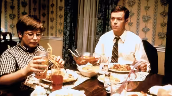 Allen (Philip Seymour Hoffman) seated at a dinner table with a boy