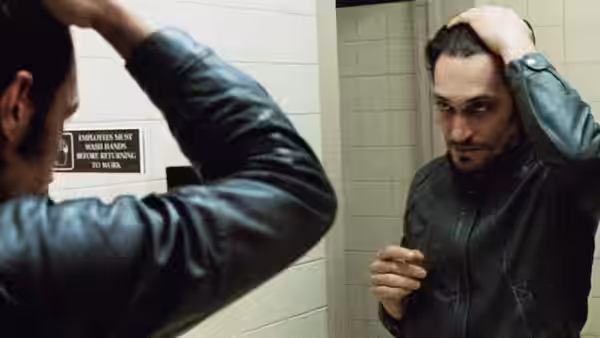Billy Brown (Vincent Gallo) adjusts his hair while looking in a bathroom mirror