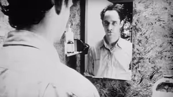 Maximillian Cohen (Sean Gullette) studies his reflection in a bathroom mirror