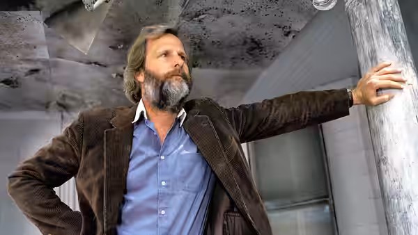 Bernard (Jeff Daniels) stands with hand on pillar in a ruined room
