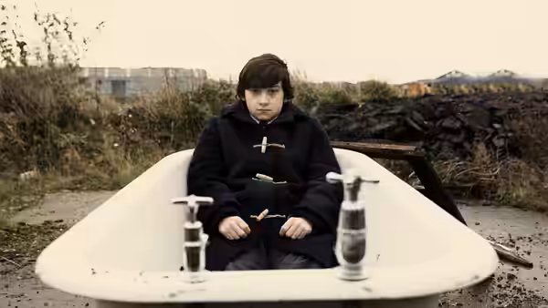 Oliver Tate (Craig Roberts) sits inside a white bathtub on open ground