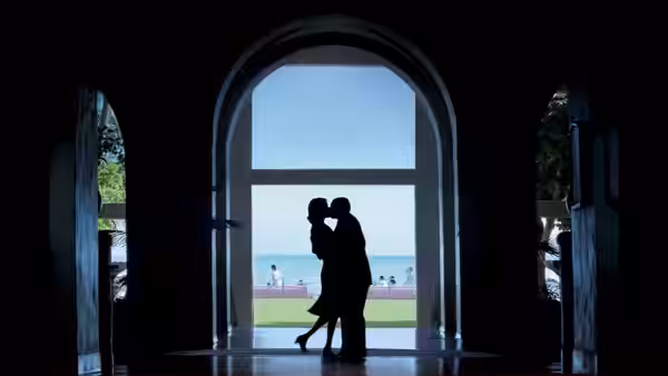 a couple embracing in a large arched doorway overlooking the ocean