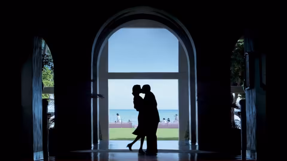 a couple embracing in a large arched doorway overlooking the ocean