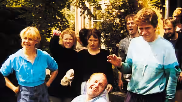 A group gathered outside a building with one person seated in a wheelchair