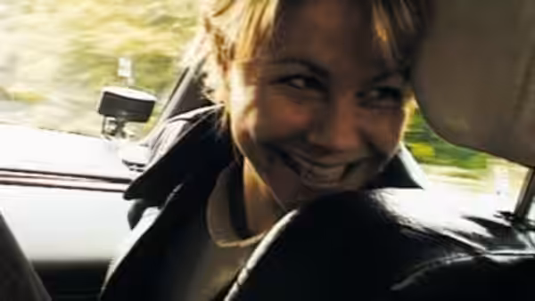 A smiling woman with short hair sitting in the passenger seat of a car