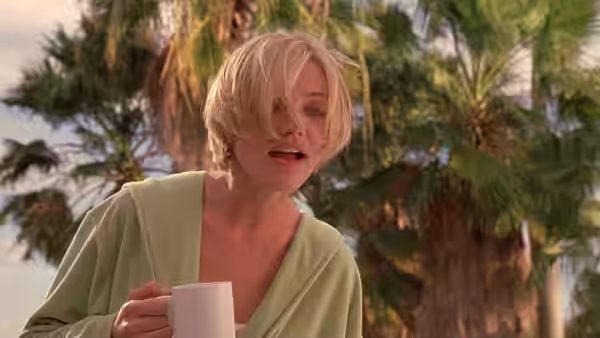 Mary (Cameron Diaz) holding a white mug outdoors among palm trees