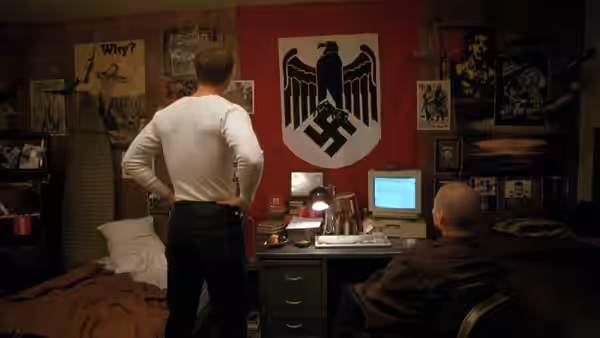 A man standing before a large Nazi flag in a bedroom