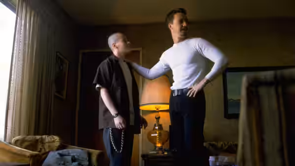 Derek (Edward Norton) resting his hand on another man's shoulder