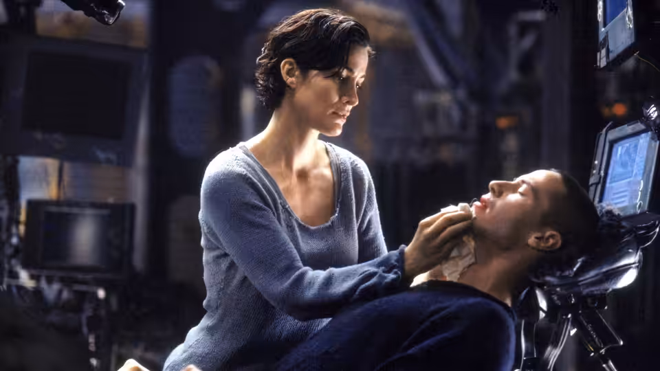 Trinity (Carrie-Anne Moss) leaning over Neo (Keanu Reeves) in a control room