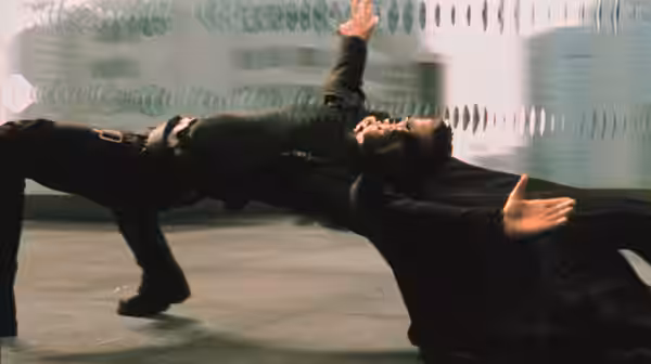 Neo (Keanu Reeves) arching backwards during a fight in an urban plaza