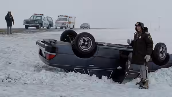 Marge Gunderson (Frances McDormand) standing beside an overturned car in snow