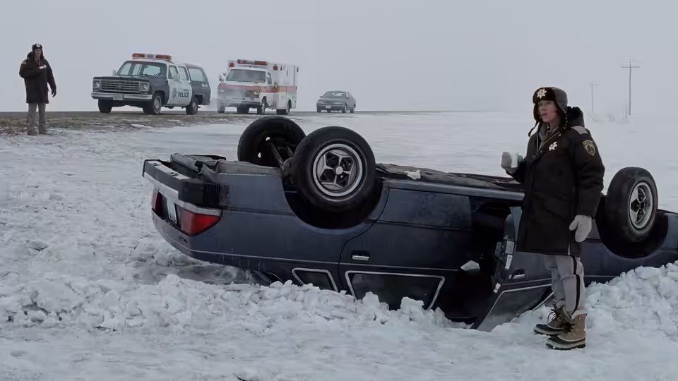 Marge Gunderson (Frances McDormand) standing beside an overturned car in snow