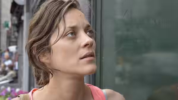 Sandra (Marion Cotillard) looks upward with a worried expression outdoors