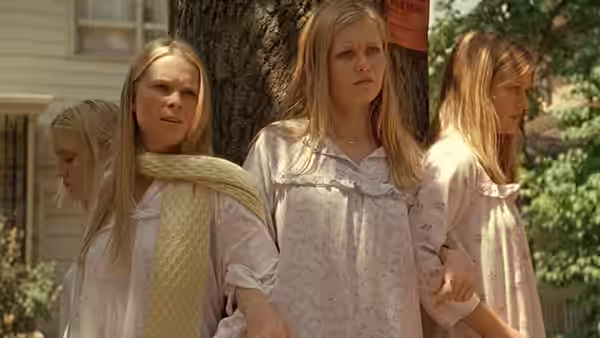 Four girls in nightgowns stand together by a tree on a suburban street