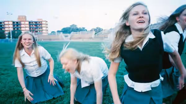 Lux Lisbon (Kirsten Dunst) and sisters in school uniforms run across a field