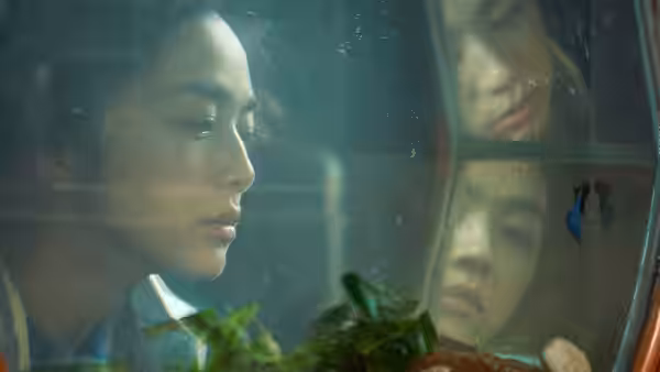 Song Seo-rae (Tang Wei) looks through a rain-speckled window, her face reflected in the glass