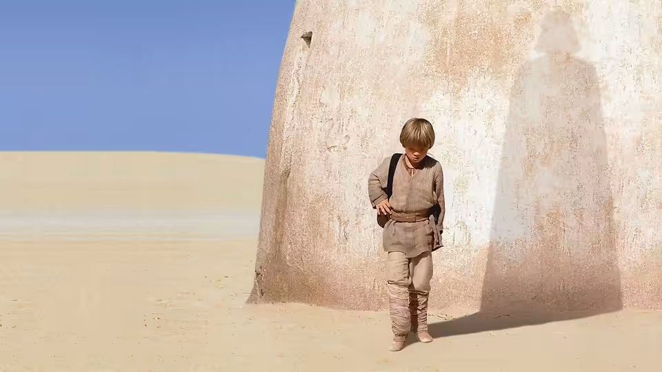 Anakin Skywalker (Jake Lloyd) standing beside a building in the desert
