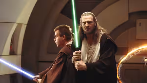 Qui-Gon Jinn (Liam Neeson) and Obi-Wan Kenobi (Ewan McGregor) holding lightsabers