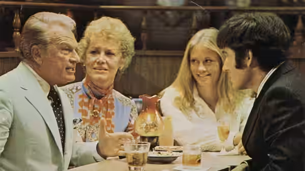 Duane Corcoran (Eddie Albert) and Mrs. Corcoran (Audra Lindley) sit with Kelly and Lenny at a table