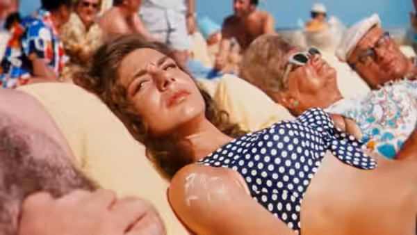 Kelly Corcoran (Cybill Shepherd) reclines on a crowded beach in a polka-dot swimsuit