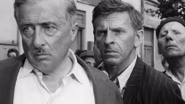 Three men stand close together on a street, looking off to the side