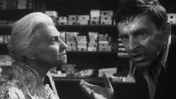 Rozalia Lautmannová (Ida Kamińska) looks up as a man gestures beside shop shelves