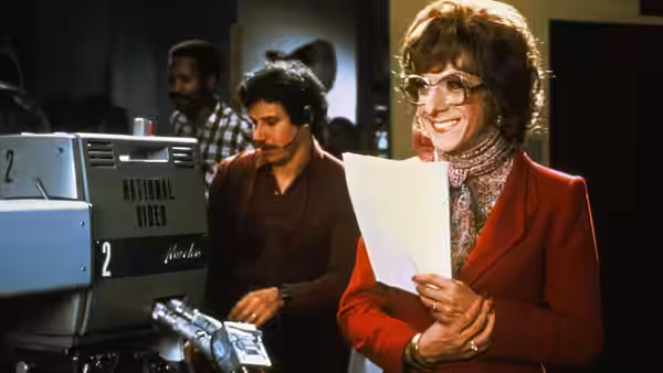 Dorothy Michaels (Dustin Hoffman) smiling with papers beside a studio camera