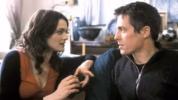 Rachel (Rachel Weisz) leans toward Will Freeman (Hugh Grant) on a sofa