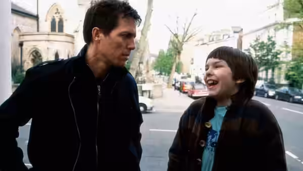 Will Freeman (Hugh Grant) walks along a city street with laughing Marcus Brewer (Nicholas Hoult)