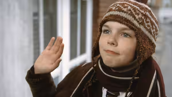Marcus Brewer (Nicholas Hoult) raises a hand outside a building