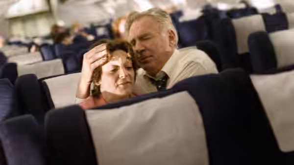 Elderly couple sits together in the seats of an airplane