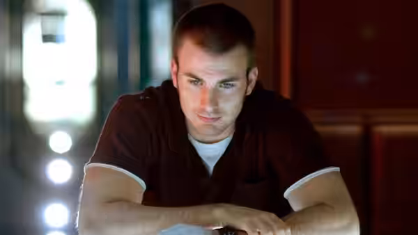 Mace (Chris Evans) seated and looking downward intently