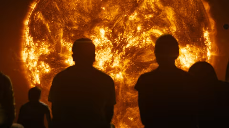 Silhouetted figures watching the sun's fiery surface