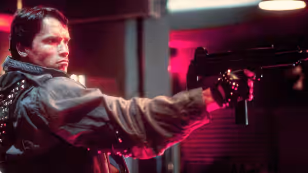 Terminator (Arnold Schwarzenegger) aiming a submachine gun in a dimly lit room