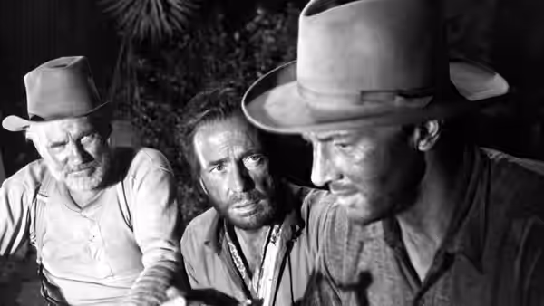 Howard (Walter Huston), Fred C. Dobbs (Humphrey Bogart) and Bob Curtin (Tim Holt) examining an object outdoors