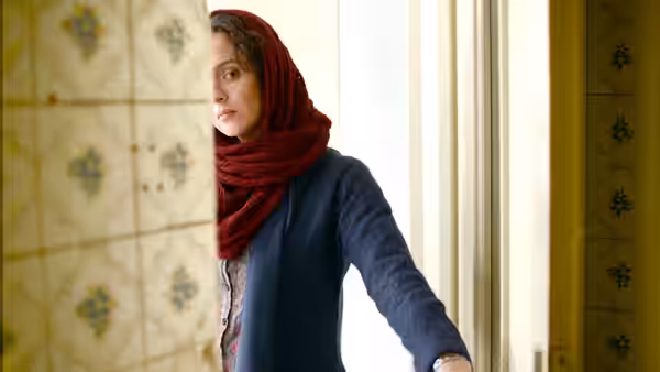 A woman in red headscarf leans out from behind a tiled doorway