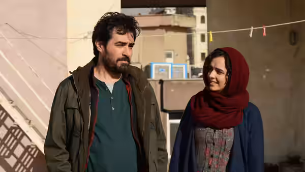 A bearded man and a woman in red headscarf stand outside together